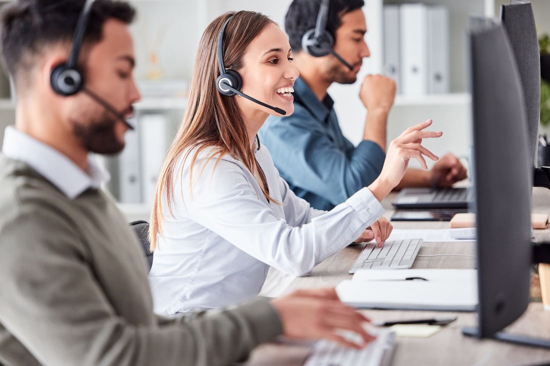 Freundliches Kundenservice-Team im Callcenter mit Headset am Arbeitsplatz Freundliches Kundenservice-Team im Callcenter mit Headset am Arbeitsplatz